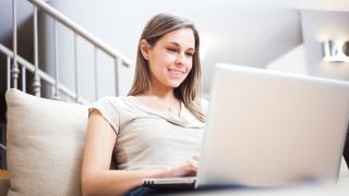 Frau schreibt auf Laptop auf Laptopkissen